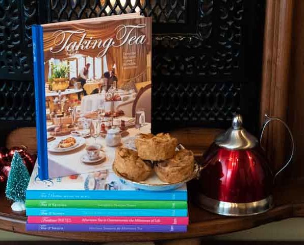 Stack of recipe books with a savory item displayed and a touch of Christmas with a kettle