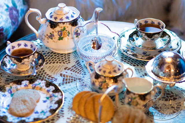 A teatime array of china, cookies, and serving trays on a lace-covered table