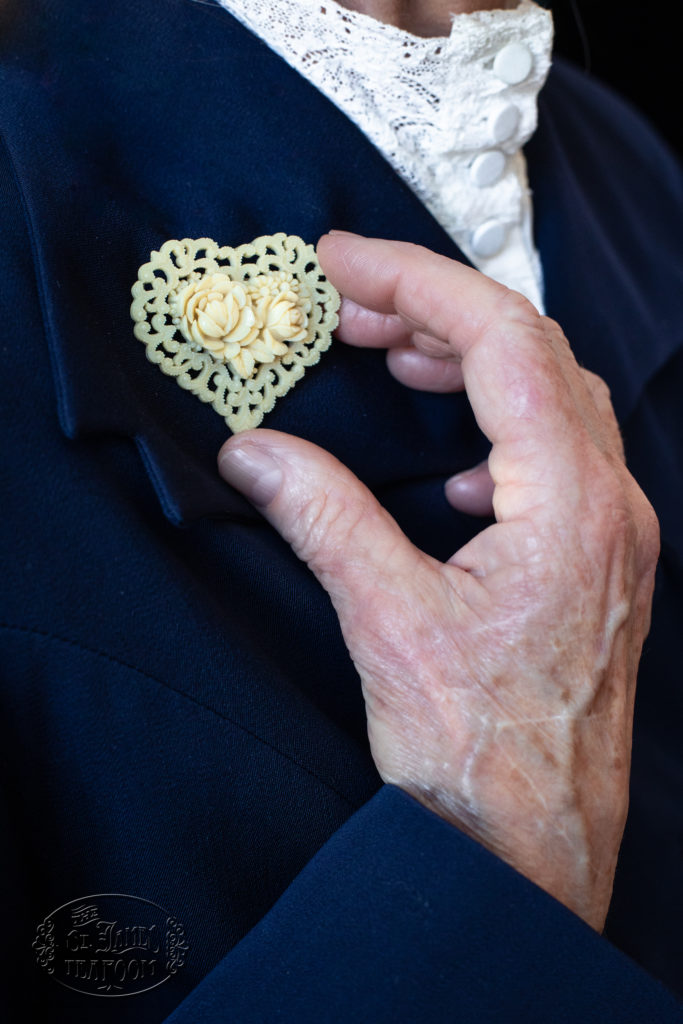 Beautiful fingers hold Mrs. Faw's dainty plastic heart pin lovingly