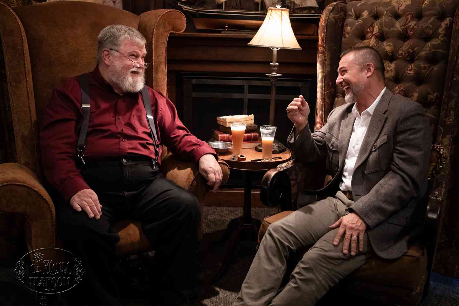 Two gentlemen sitting in arm chairs and laughing